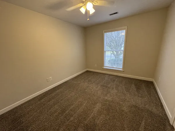 an empty room with windows and fan