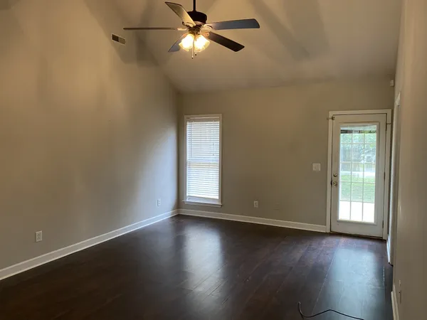 an empty room with wooden floor fan and windows