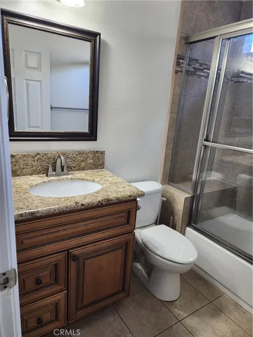 a bathroom with a granite countertop toilet sink and mirror