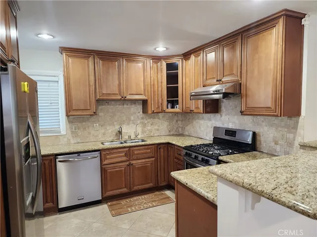 a kitchen with stainless steel appliances granite countertop wooden cabinets a sink and dishwasher