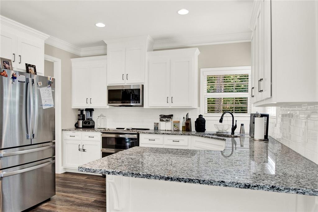 407 Corinth Church Road Winder, GA 30680 - Photo 21 of 66 a kitchen with granite countertop a sink a counter top space cabinets stainless steel appliances and a window