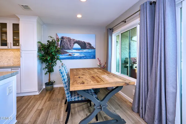 a kitchen with granite countertop a table chairs stove a refrigerator and a potted plant