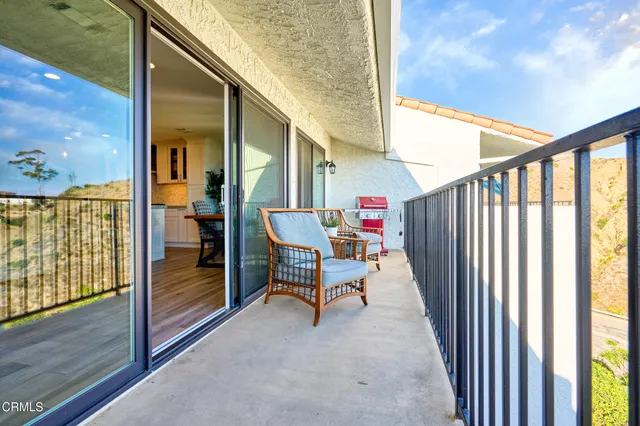 a living room with stainless steel appliances furniture refrigerator and a kitchen view