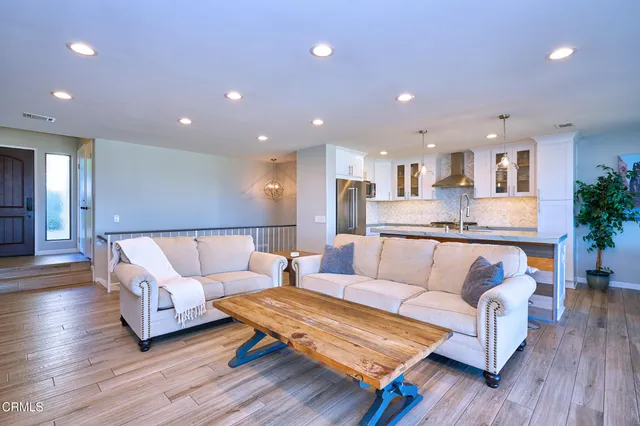 a living room with stainless steel appliances furniture and a kitchen view
