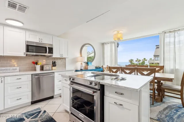 a kitchen with stainless steel appliances granite countertop a sink a stove a refrigerator a microwave a table and chairs