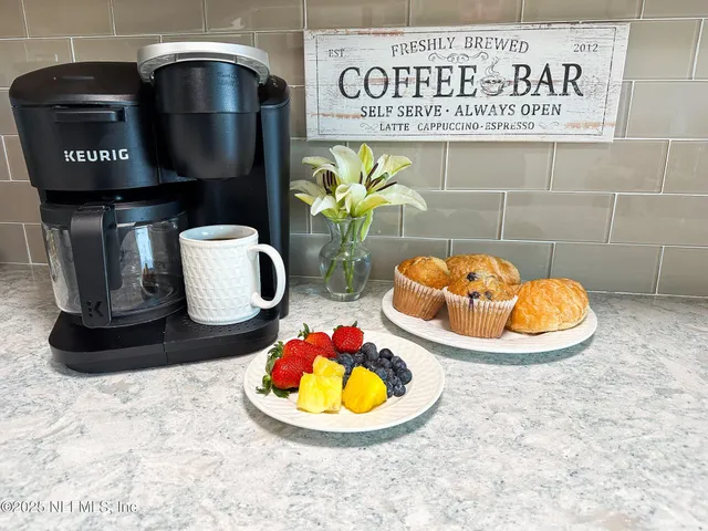 a kitchen with stainless steel appliances granite countertop a stove a sink a refrigerator white cabinets and chairs