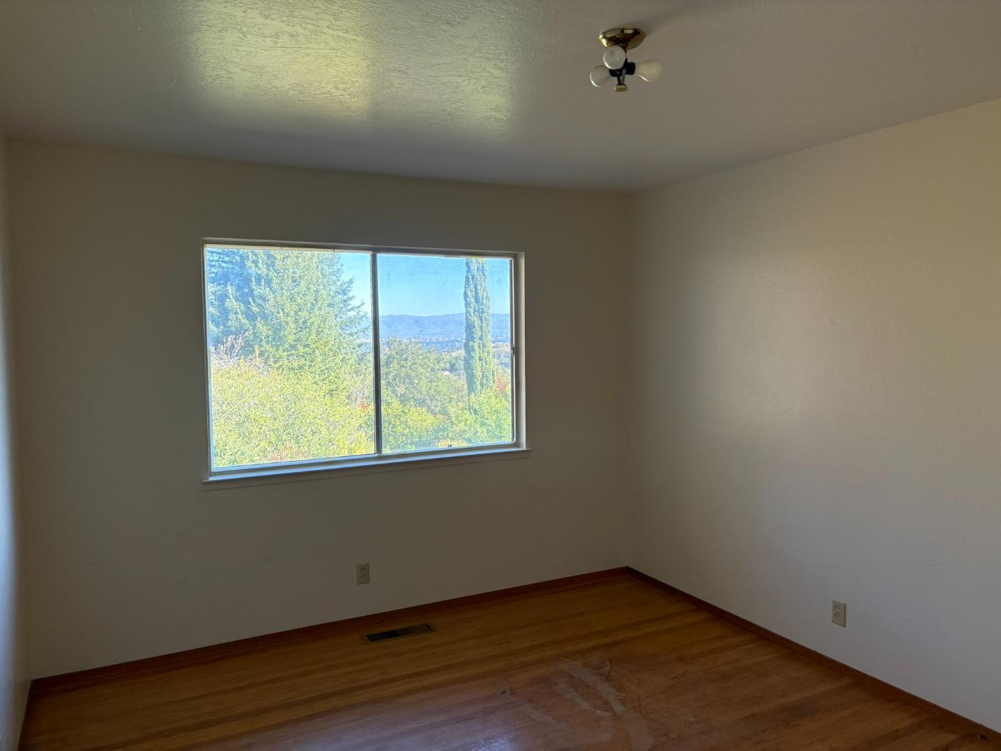 12130 Foothill Lane Los Altos Hills, CA 94022 - Photo 6 of 13 an empty room with wooden floor and windows