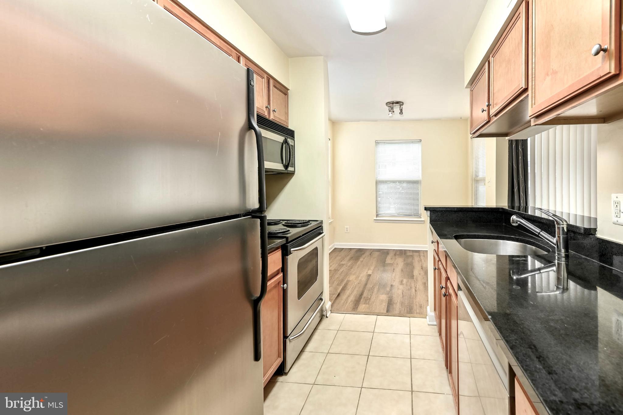 1706 Ascot Way, Unit B Reston, VA 20190 - Photo 7 of 14 a kitchen with granite countertop a refrigerator a sink a stove and white cabinets