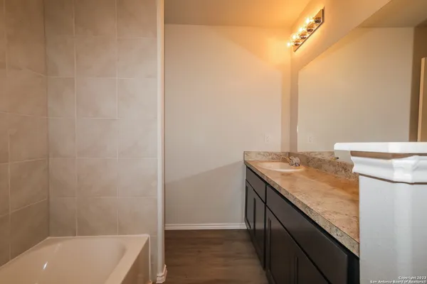 a bathroom with a granite countertop sink and a bathtub
