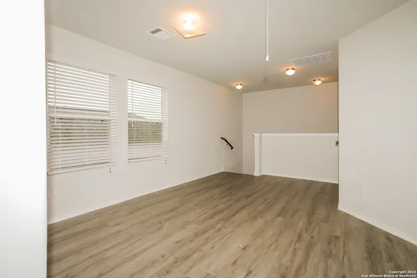 a view of empty room with wooden floor and fan
