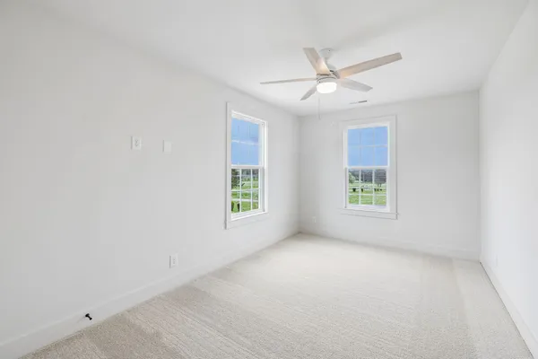 an empty room with windows and ceiling fan