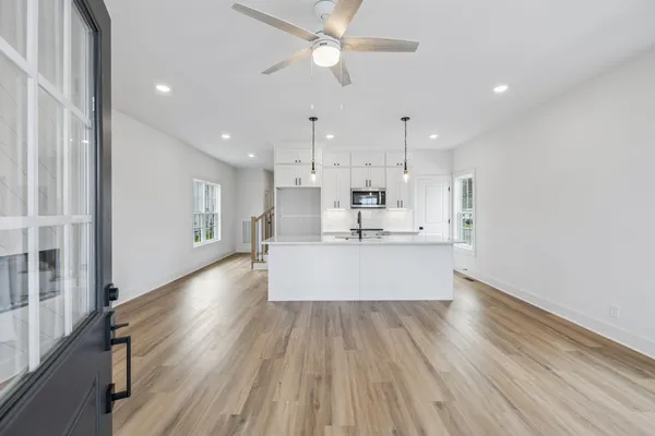 a view of kitchen with kitchen island wooden floors appliances and cabinets