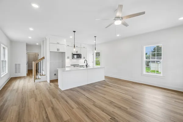 a view of an empty room with a window and kitchen view
