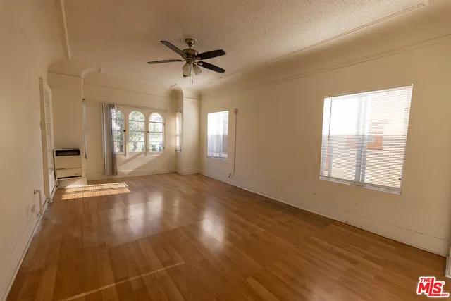 a view of empty room with wooden floor and fan