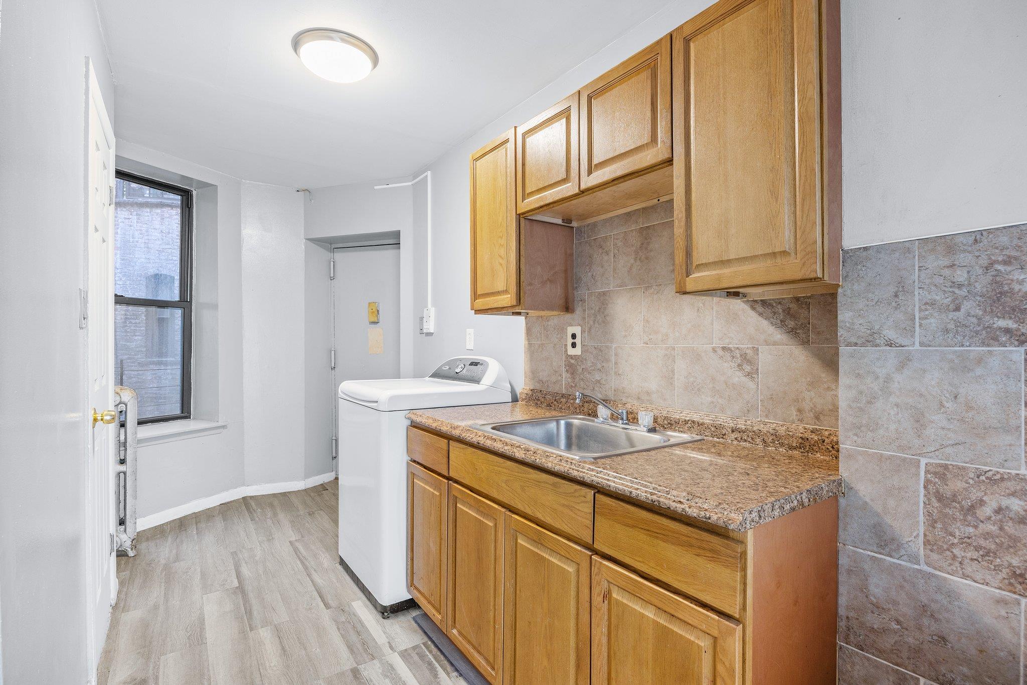 72 Richardson Street, Unit 4 Brooklyn, NY 11211 - Photo 11 of 17 Kitchen with light wood-style flooring, a sink, baseboards, decorative backsplash, and washer / clothes dryer