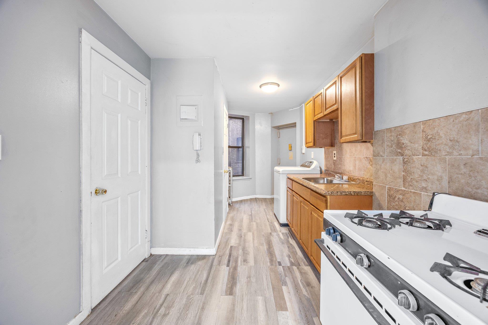 72 Richardson Street, Unit 4 Brooklyn, NY 11211 - Photo 12 of 17 Kitchen featuring white range with gas stovetop, washer / clothes dryer, baseboards, light wood finished floors, and a sink