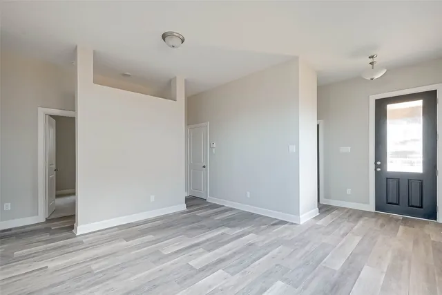 a view of an empty room with wooden floor and window