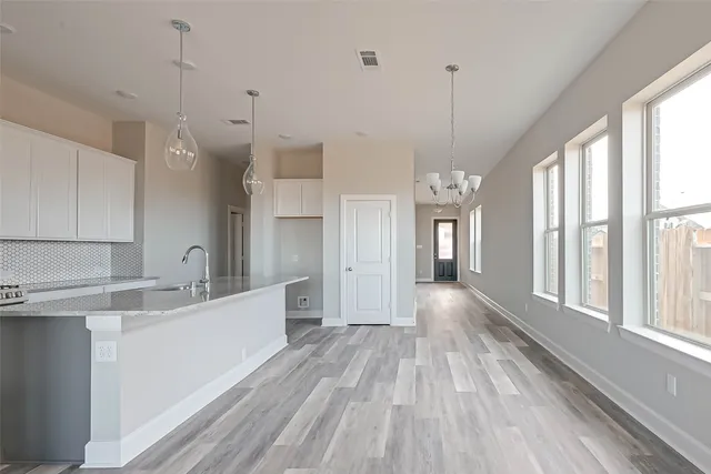 a view of a kitchen and an empty room with windows