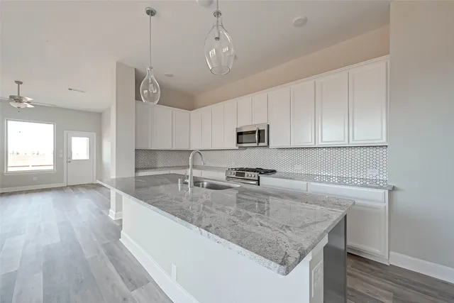 a kitchen with granite countertop a sink a counter space appliances and cabinets