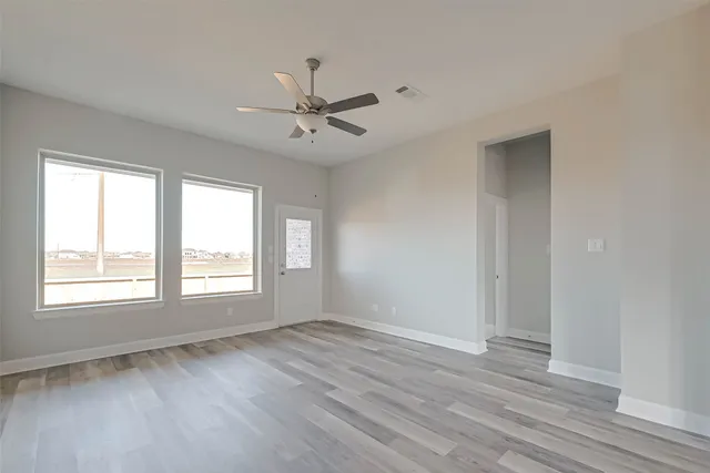 a view of an empty room with wooden floor and a window