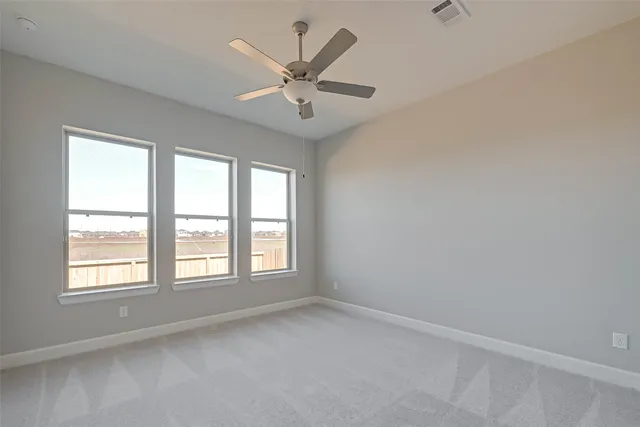 an empty room with windows and fan