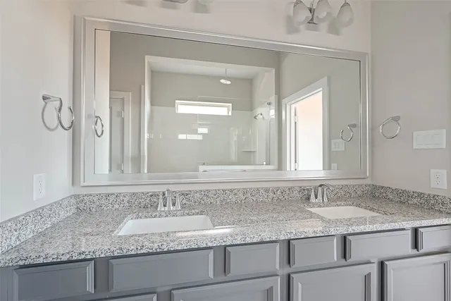 a bathroom with granite countertop double vanity sink and two mirror