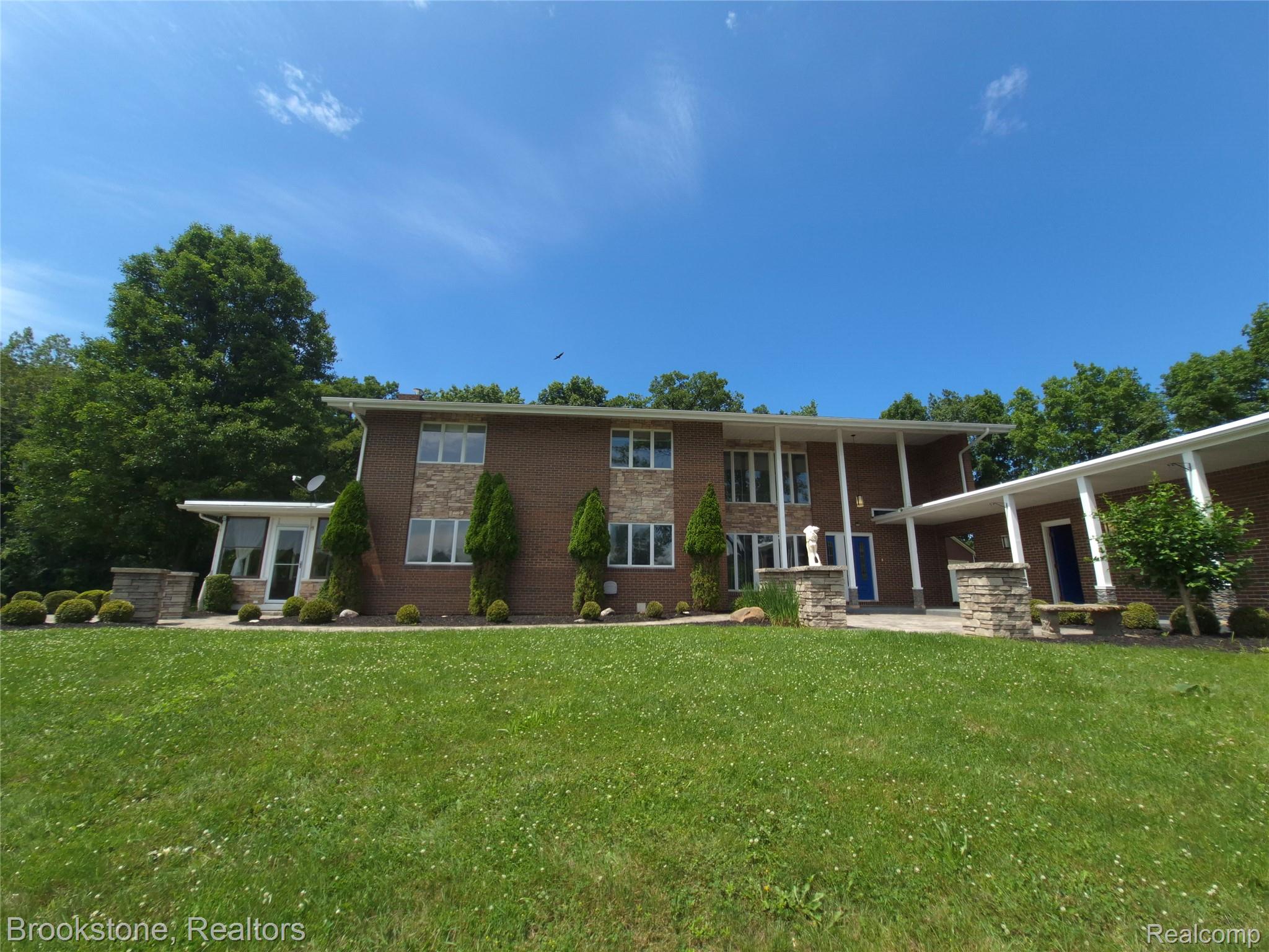 4140 South Henderson Road Davison, MI 48423 - Photo 2 of 98 Brick exterior with stone veneer accents, multiple large windows, a covered entrance, and mature landscaping