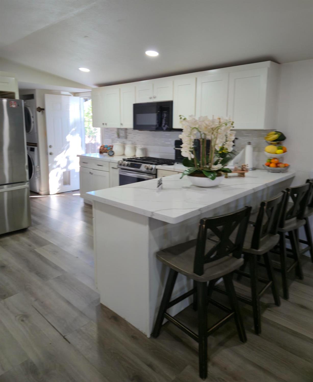 1284 Elizabeth Street, Unit 80 Coalinga, CA 93210 - Photo 6 of 24 a kitchen with a dining table chairs refrigerator and microwave