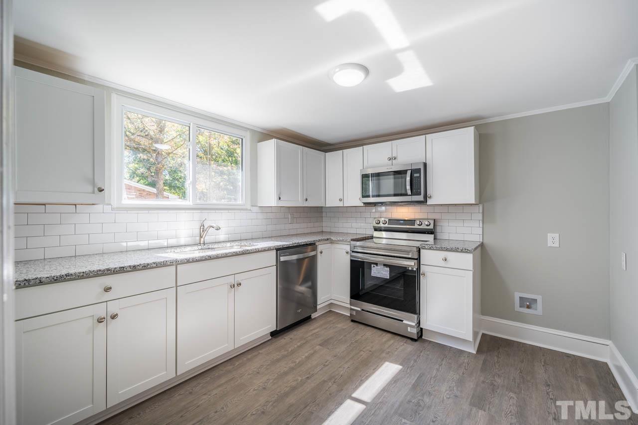 305 School House Road Efland, NC 27243 - Photo 31 of 35 a kitchen with granite countertop white cabinets appliances a sink and a window
