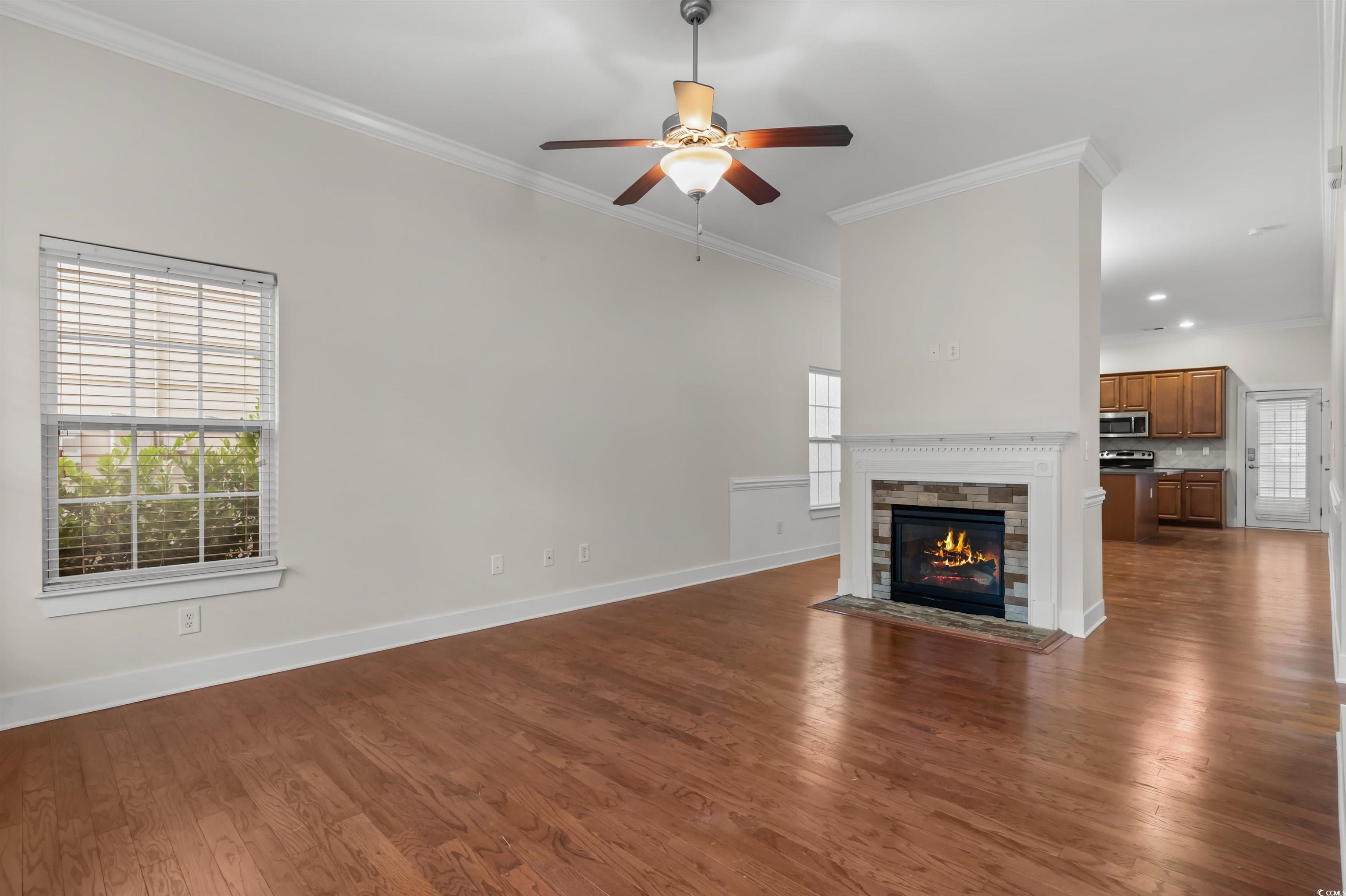 2006 Heritage Loop Myrtle Beach, SC 29577 - Photo 3 of 33 Unfurnished living room with dark wood-style floors, ornamental molding, a fireplace with flush hearth, and a ceiling fan