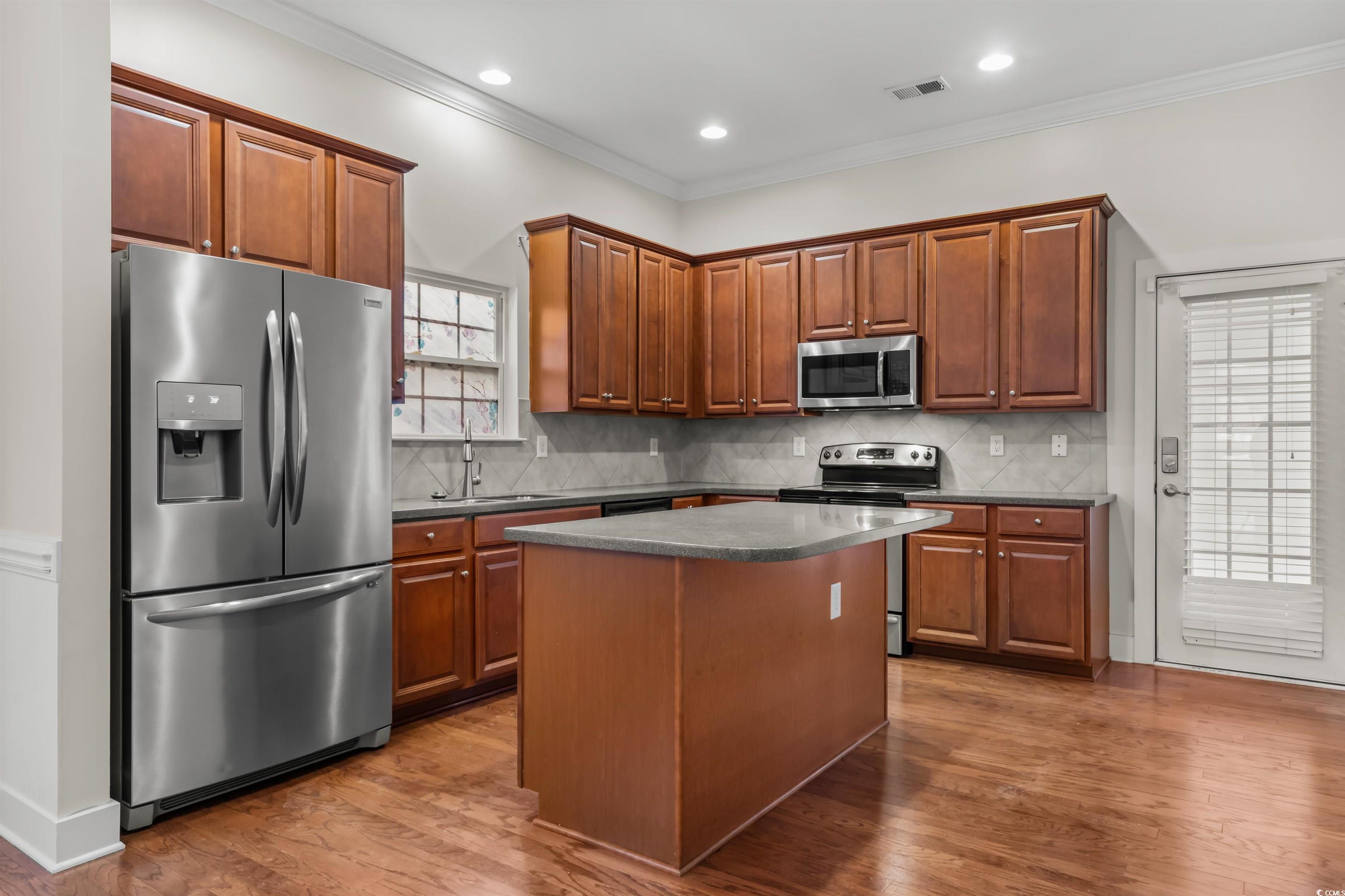 2006 Heritage Loop Myrtle Beach, SC 29577 - Photo 10 of 33 Kitchen with appliances with stainless steel finishes, crown molding, dark countertops, tasteful backsplash, and dark wood-style flooring