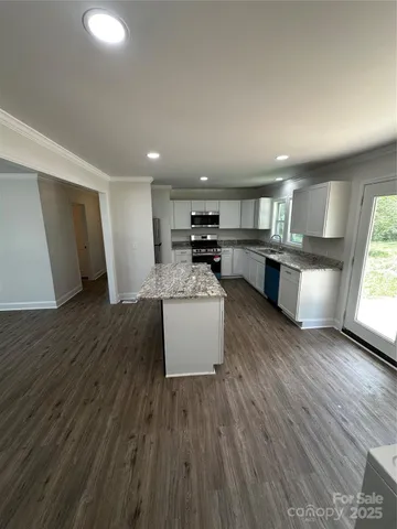 a kitchen with a sink dishwasher stove and wooden floor