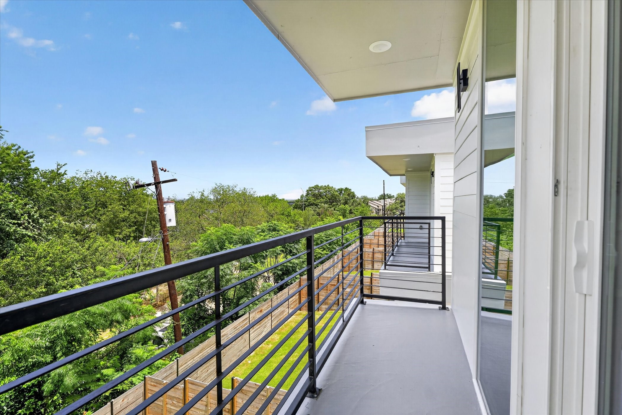 2000 Riverside Farms Road, Unit 8101 Austin, TX 78741 - Photo 17 of 41 This photo showcases a modern balcony with sleek railing, offering a view of lush greenery and a clear blue sky, perfect for enjoying outdoor relaxation.