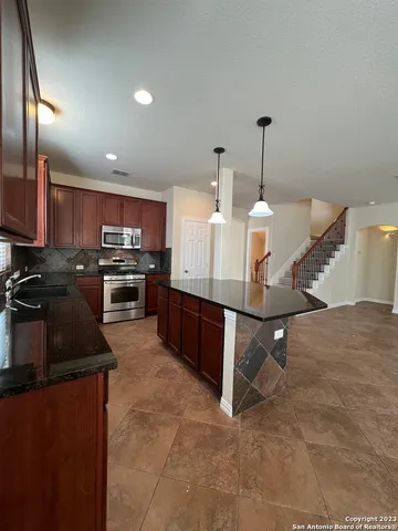 a kitchen with stainless steel appliances kitchen island granite countertop a stove refrigerator and cabinets