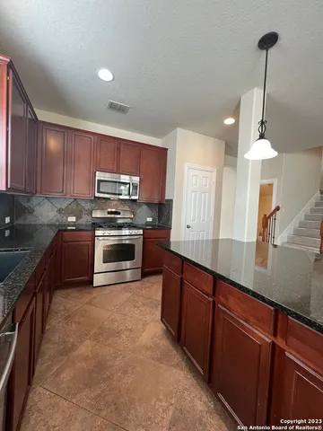 a kitchen with stainless steel appliances a sink a stove a microwave a center island and cabinets
