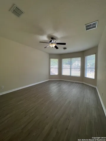 a view of an empty room with wooden floor and a window