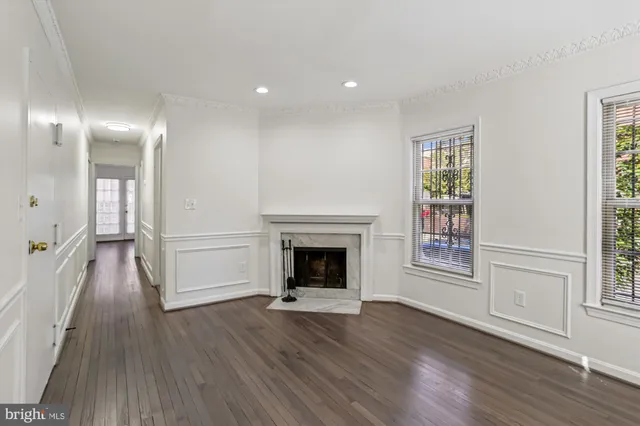 an empty room with wooden floor fireplace and windows
