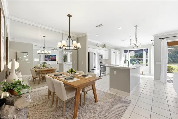 a dining room filled with furniture a chandelier and kitchen view