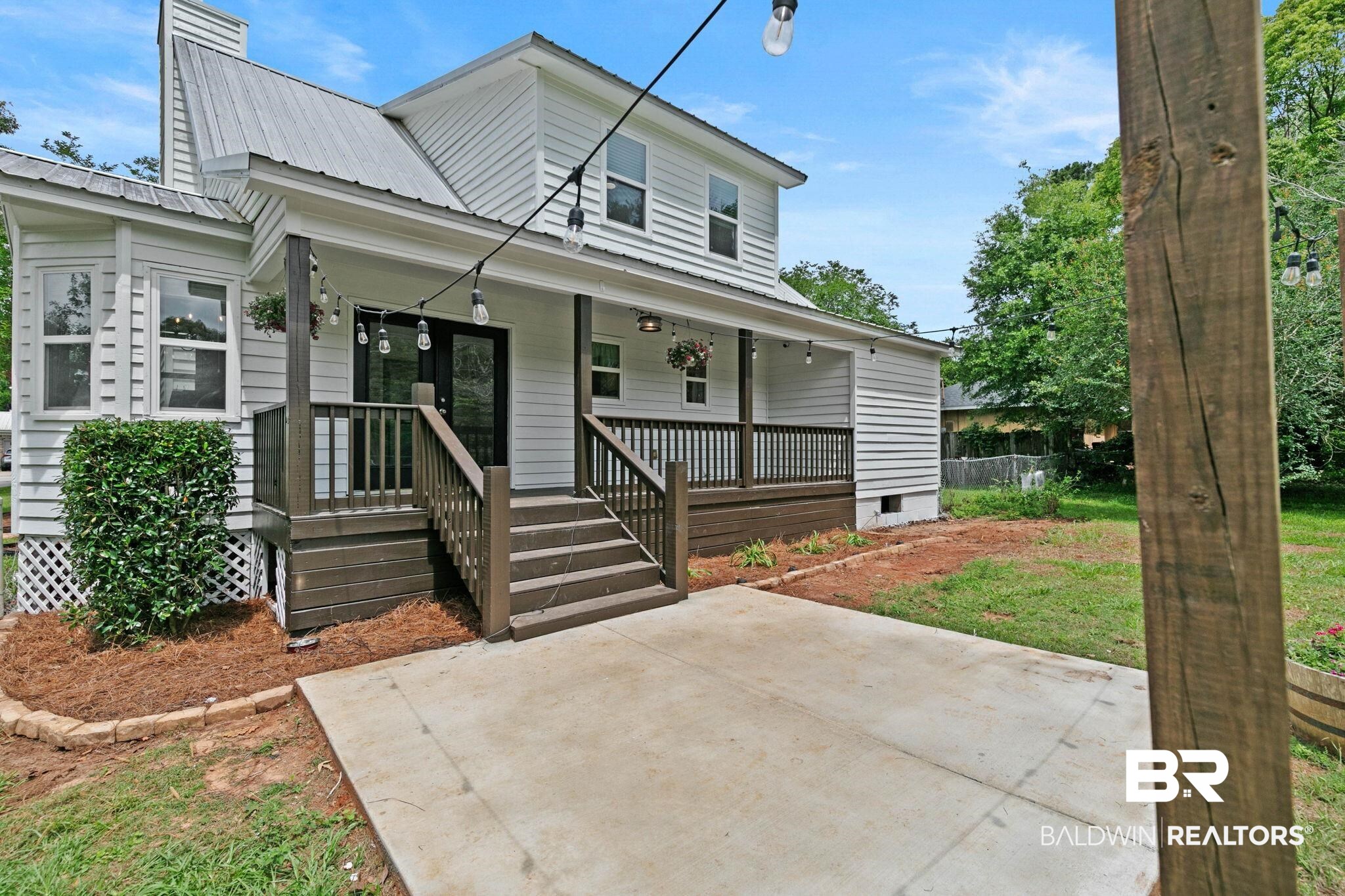 22810 High Ridge Road Fairhope, AL 36532 - Photo 58 of 78 White siding exterior with a metal roof, featuring a covered porch with dark railings and steps