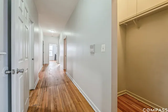 a view of a hallway with wooden floor and a bathroom