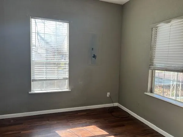 a view of an empty room with wooden floor and a window
