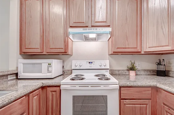a kitchen with granite countertop wood cabinets and white appliances