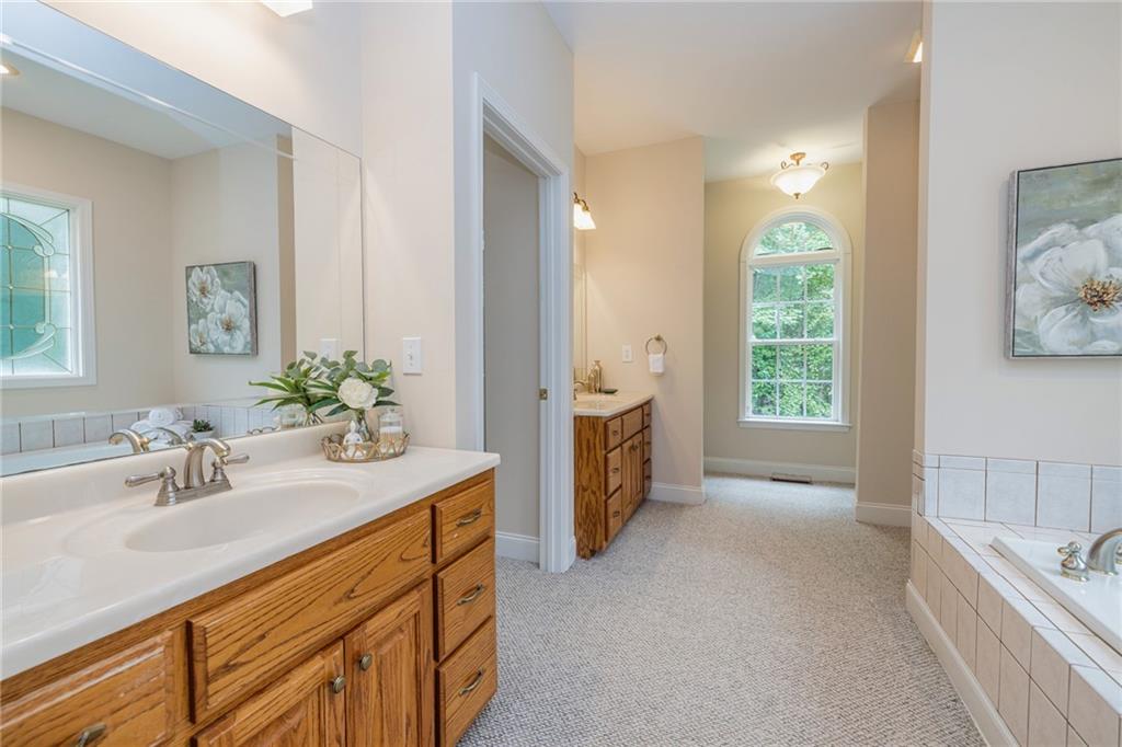 394 South Alexander Creek Road Newnan, GA 30263 - Photo 30 of 76 a spacious bathroom with a double vanity sink a large mirror a bathtub and next to a window