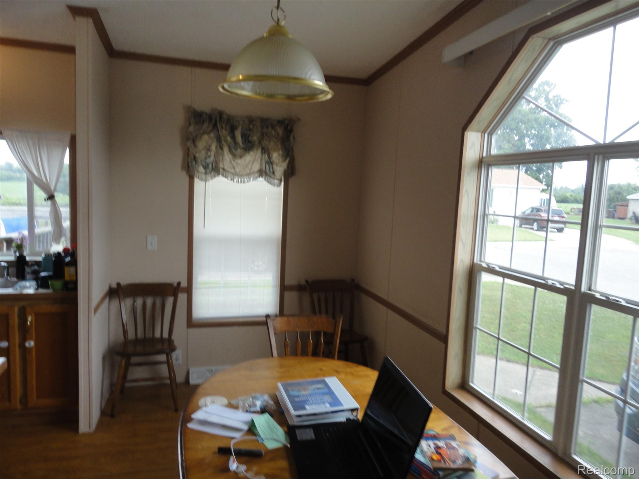 5931 Megans Ridge Monroe, MI 48161 - Photo 8 of 13 Dining area featuring a prominent angled window, light wood-finish flooring, a domed ceiling fixture, and neutral wall paneling