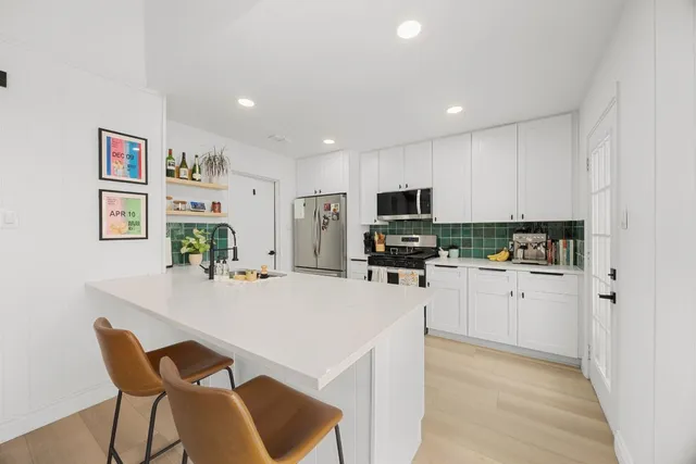a kitchen with white cabinets and stainless steel appliances