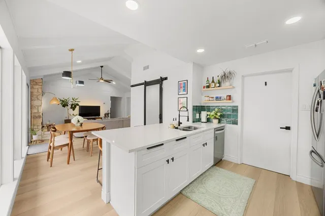 a large kitchen with kitchen island a sink a stove a refrigerator and a dining table with wooden floor