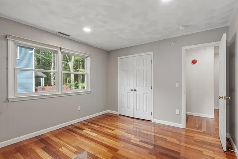a view of an empty room with wooden floor and windows
