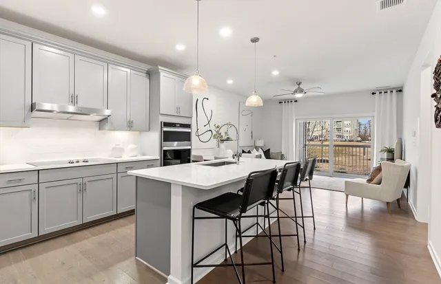 a kitchen with stainless steel appliances kitchen island granite countertop a table chairs sink and cabinets
