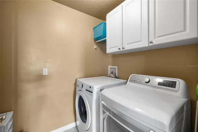a backyard of a house with table and chairs plants and large tree