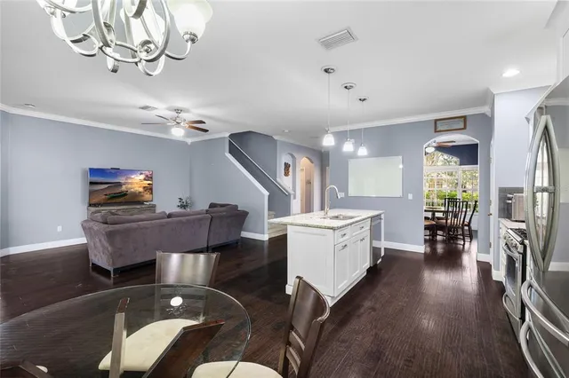 a dining room with wooden floor a chandelier a wooden table and chairs